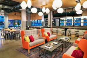 a library with orange chairs and tables and a bar at Aloft Louisville Downtown in Louisville