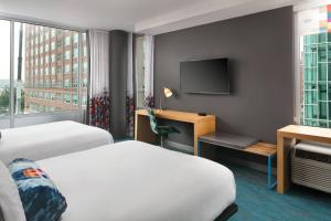a hotel room with two beds and a television at Aloft Louisville Downtown in Louisville