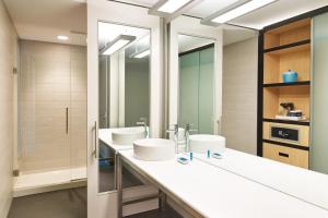 a bathroom with two sinks and two mirrors at Aloft Louisville Downtown in Louisville