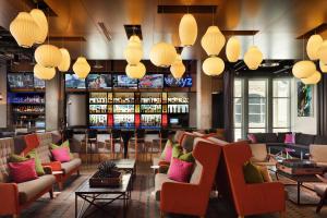 a lobby with chairs and a bar with drinks at Aloft Louisville Downtown in Louisville