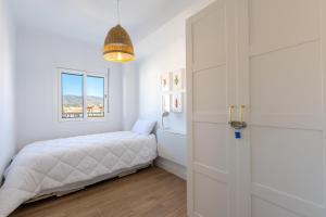 um quarto branco com uma cama e uma janela em Piso Estrella 031 em Torre del Mar