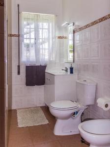 a white bathroom with a toilet and a sink at Porto Martins Bay Apartments AL in Porto Martins
