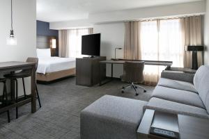 a hotel room with a bed and a couch and a desk at Residence Inn by Marriott Tulsa South in Tulsa