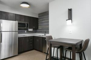 a kitchen with a table and a stainless steel refrigerator at Residence Inn by Marriott Tulsa South in Tulsa