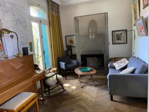 a living room with a blue couch and a piano at Villa avec piscine en plein cœur de ville in Montpellier