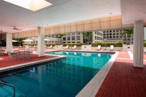 - une piscine dans un hôtel avec des tables et des chaises dans l'établissement Miami Marriott Dadeland, à Miami