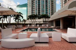 une terrasse avec des chaises blanches, une piscine et des bâtiments dans l'établissement Miami Marriott Dadeland, à Miami