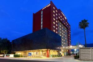a hotel with a red building with a palm tree at Courtyard Monterrey San Jeronimo in Monterrey