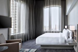 1 dormitorio con cama blanca y ventana grande en AC Hotel by Marriott Grand Rapids Downtown, en Grand Rapids