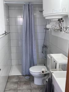 baño con aseo y cortina de ducha azul en Drago y Laurel, en Taibique