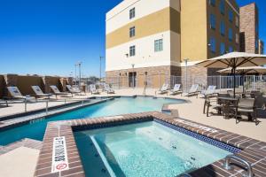 a swimming pool with chairs and a table and a building at Fairfield Inn & Suites by Marriott Fort Stockton in Fort Stockton