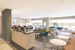 a lobby with a waiting area with tables and chairs at TownePlace Suites by Marriott Hamilton in Hamilton