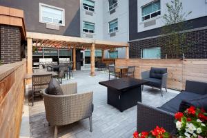 a patio with furniture and tables and a building at TownePlace Suites by Marriott Hamilton in Hamilton