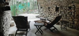 Zimmer mit 2 Stühlen, einem Tisch und einer Steinmauer in der Unterkunft Mas de la Filoselle in Saint-Martin-de-Valgalgues