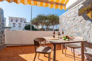 d'une terrasse avec une table et des chaises ainsi qu'un mur en pierre. dans l'établissement Apartamento con terraza cerca de la playa by InsideHome, à Empuriabrava