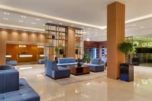 un hall avec des chaises et des tables bleues et un pilier dans l'établissement Courtyard by Marriott Tashkent, à Tachkent