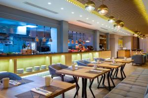 un restaurant avec des tables et des chaises en bois ainsi qu'un bar dans l'établissement Courtyard by Marriott Tashkent, à Tachkent