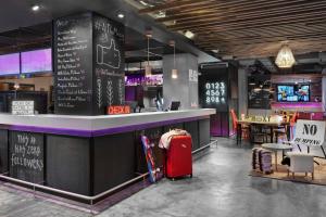 a restaurant with a bar with a red suitcase at Moxy Bucharest Old Town in Bucharest