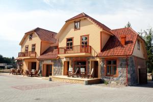 a large house with a balcony and tables and chairs at Veski Külalistemaja in Kantküla