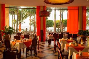 a restaurant with tables and chairs and palm trees at Protea Hotel by Marriott Entebbe in Entebbe