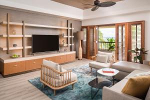 a living room with a television and a couch and chairs at Sheraton Kauai Coconut Beach Resort in Kapaa