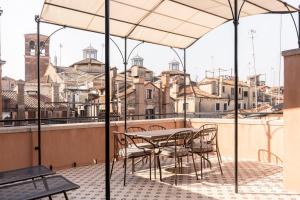 una mesa y sillas bajo una sombrilla en el balcón en Be Mate Ponte di Rialto, en Venecia