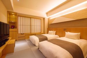 a hotel room with two beds and a flat screen tv at Cocochee Hotel Numazu in Numazu
