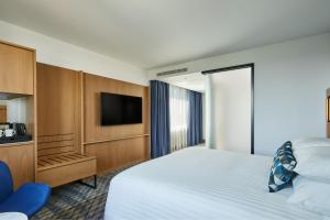 a hotel room with a bed and a flat screen tv at Courtyard by Marriott Exeter Sandy Park in Exeter