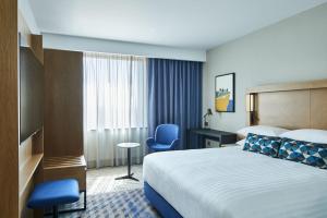 a hotel room with a bed and a blue chair at Courtyard by Marriott Exeter Sandy Park in Exeter