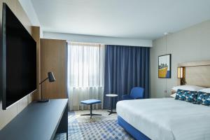a hotel room with a bed and a flat screen tv at Courtyard by Marriott Exeter Sandy Park in Exeter