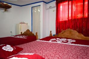a bedroom with two beds with red covers and a window at Casa colonial Villa Victoria Appartement 3 in Trinidad
