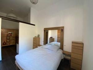 1 dormitorio con 1 cama blanca grande y espejo en Maison 3 chambres cour/bassin, en Pernes-les-Fontaines