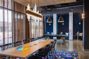 プロビデンスにあるAloft Providence Downtownの木製のテーブルと椅子、大きな窓のあるレストランを併設しています。