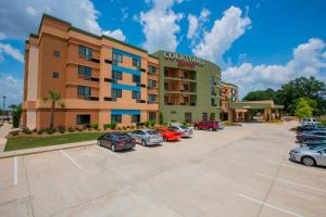 ein Hotel mit Autos auf einem Parkplatz in der Unterkunft Courtyard by Marriott Jackson Airport/Pearl in Pearl