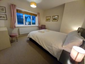 a bedroom with a white bed and a window at Grange Croft in Ben Rhydding