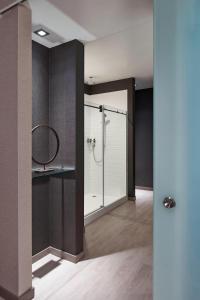 a bathroom with a glass shower with a mirror at AC Hotel by Marriott Des Moines East Village in Des Moines