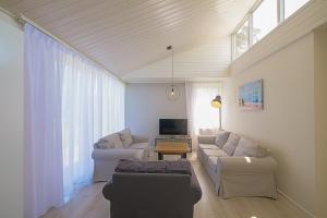 een woonkamer met 2 banken en een tv bij Familiehuis Noordenwind - Julianadorp aan Zee in Julianadorp