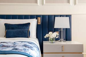 a blue and white bedroom with a bed and a table with a lamp at The St. Regis Doha in Doha