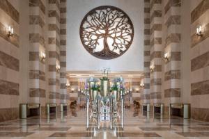 a lobby with a large tree mural on the wall at The St. Regis Doha in Doha