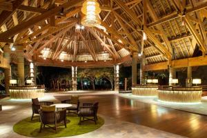 un grand hall avec des plafonds en bois, des tables et des chaises dans l'établissement Sheraton New Caledonia Deva Spa & Golf Resort, à Bourail