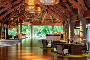 un vestíbulo con techos de madera, mesas y sillas en Sheraton New Caledonia Deva Spa & Golf Resort, en Bourail