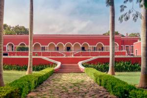 a red building with palm trees in front of it at Hacienda Temozon in Abalá