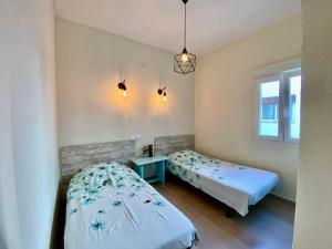 a bedroom with two beds and a table and a window at Apartment Monica by Moraira Holiday Homes in Moraira