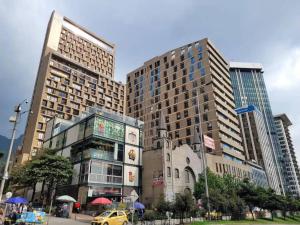 twee hoge gebouwen in een stad met een gele auto bij Acogedor loft en Centro Internacional de Bogotá in Bogota