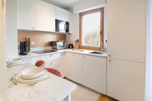 eine Küche mit weißen Schränken, einem Tisch und einem Fenster in der Unterkunft The Green Home - Quiet and Fully Equipped High-End Studio with parking in Courcouronnes