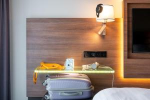 a bed room with a table with luggage and a lamp at Moxy Amsterdam Houthavens in Amsterdam