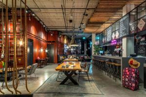 a restaurant with a table and chairs and a bar at Moxy Amsterdam Houthavens in Amsterdam