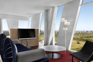 a living room with a tv and chairs and a table at AC Hotel by Marriott Bella Sky Copenhagen in Copenhagen