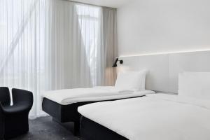 a hotel room with two beds and a chair at AC Hotel by Marriott Bella Sky Copenhagen in Copenhagen