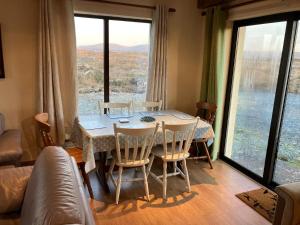a dining room table with chairs and a large window at Glynsk Pier Cottage in Carna